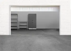 Empty garage with gray concrete floor, two empty shelves on the left