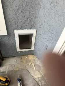 Pet door installed on textured wall.