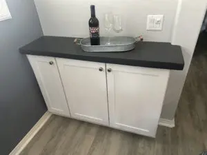 White cabinet with wine bottle and glasses.